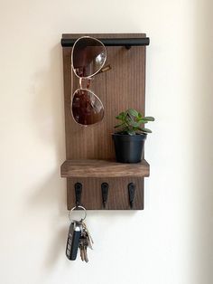 a wall mounted shelf with sunglasses and keys on it next to a potted plant