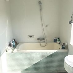 a bath tub sitting next to a white toilet under a shower head and faucet