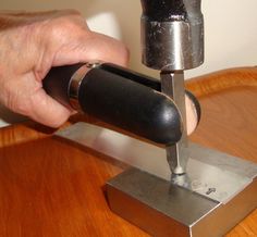 a man is using a drill to fix a piece of metal on a wooden table