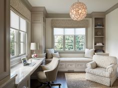 a room that has a couch, desk and chair in it with a lamp hanging from the ceiling