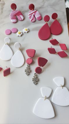 several pairs of pink and white earrings are laying on a counter top next to each other