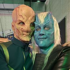 two people dressed in green and blue are posing for the camera with their heads together