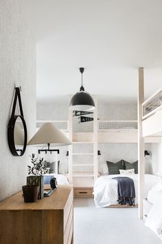 a bedroom with bunk beds and two lamps hanging from the ceiling, along with other furniture