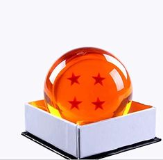 an orange ball with red stars on it in a white display case and black stand