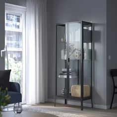 a living room with a chair and a glass cabinet