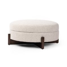 a round ottoman sitting on top of a white floor next to a wooden frame and foot rest