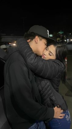 a man and woman embracing each other in the back of a car at night time