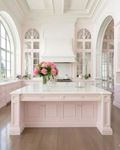 a large kitchen with pink cabinets and white counter tops