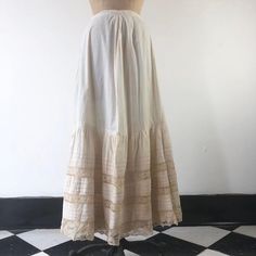 Antique Victorian cotton maxi skirt has horizontal pleats, and lace ribbon insets at the hem. The skirt has clasp closures, and an underskirt at the hem portion of the skirt. ConditionStructurally good, with issues. Has overall yellowing, with darker areas, and stains throughout but most prominently in the hem area. There are tiny dot stains on the upper skirt portion. There’s two area of holes in the lace at the hem.  The underskirt has staining throughout. We have not attempted to clean this i Beige Long Skirt With Lace Trim, Beige Cotton Skirt With Lace Trim, Summer Cotton Skirt With Attached Cancan, Vintage Long Lace Skirt, Daywear Long Lace Skirt, Elegant Ruffled Maxi Skirt For Daywear, Vintage Long Skirt With Attached Cancan, Long Cotton Skirt With Lace Trim, Daywear Tiered Gathered Petticoat