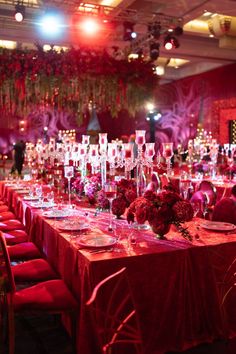 a long table is set up with red chairs and centerpieces for an event