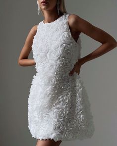 a woman in a white dress with flowers on it's back, posing for the camera