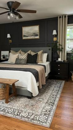 a bedroom with black walls and white bedding has a rug on the wooden floor