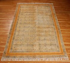 an old rug with fringes on the floor in front of a wooden flooring