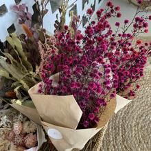 purple flowers are wrapped in brown paper and placed on the floor next to other items