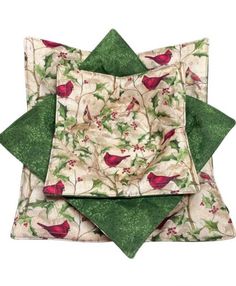 three green and white square pillows with red birds on the bottom one is folded in half