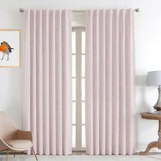 a living room with pink curtains and a chair in front of a window that has an orange bird on it