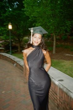 a woman wearing a graduation cap and gown posing for the camera with her hands on her hips