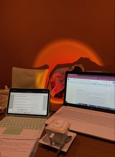 two laptop computers sitting on top of a wooden table