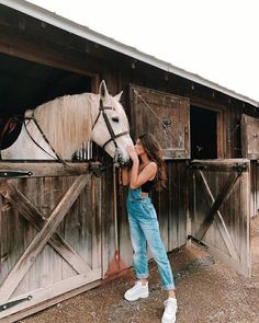 a woman is petting a white horse in front of a wooden barn with the words, look at that 11 horseseee