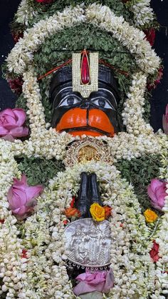 the statue is decorated with flowers and other things to decorate on it's face