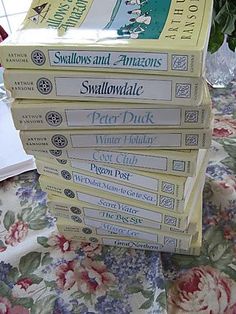 a stack of books sitting on top of a table next to a potted plant