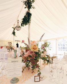 the table is set up with flowers and wine glasses for an elegant wedding reception in a marquee