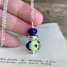 This necklace features a Beautiful Artisan glass lampwork bead with a tropical lime green core encased in clear glass with cobalt blue polka dots. Layered with a large chunky sterling silver saucer and a matching cobalt blue lampwork glass spacer bead. Finished with two sterling silver round beads in 2 and 3mm. Hung on an 18 inch sterling silver chain with a hand wrapped lobster clasp. One of a kind To view more of my handmade Jewelry, Accessories and Gifts please click here ---->http;//www.D Green Recycled Glass Bead Jewelry, Green Recycled Glass Round Bead Jewelry, Recycled Glass Round Beads Jewelry For Gifts, Recycled Glass Round Beads Jewelry Gift, Green Glass Pendant Jewelry, Green Glass Jewelry As Gift, Green Glass Jewelry Gift, Green Glass Jewelry As A Gift, Green Recycled Glass Necklaces For Jewelry Making