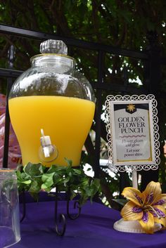 a table topped with a vase filled with orange juice and a sign next to it