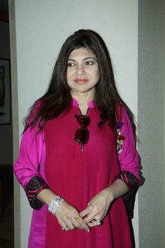 a woman in a pink dress standing next to a wall