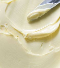 a knife sitting on top of a white cake frosted with cream cheese icing