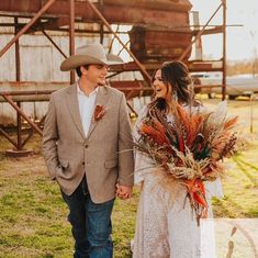 a man and woman holding hands while standing next to each other in front of an old barn