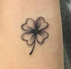 a small four leaf clover tattoo on the right arm and leg, with black ink