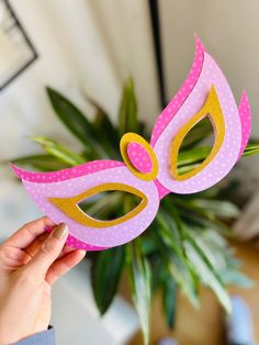 a person holding up a pink and yellow mask