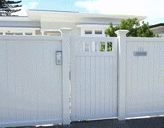 a white fence and gate in front of a house