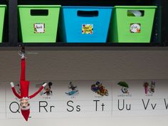 an elf is hanging upside down in front of several bins with letters on them