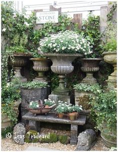 an outdoor garden with potted plants and flowers on the wall, along with a stone bench