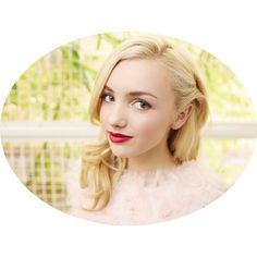 a woman with blonde hair and red lipstick posing for a photo in front of a window