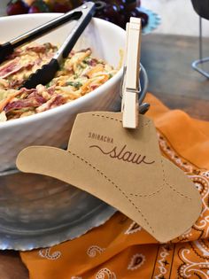 a bowl of food on a table next to utensils and a paper tag