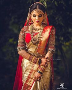 a woman in a red and gold bridal outfit with her hands on her hip