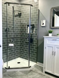 a walk in shower sitting next to a white cabinet and sink on top of a tiled floor