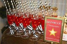 there are many wine glasses on the table with straws in them and a sign that says lizzy wood champagne