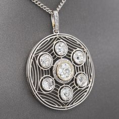 This enticing Art Deco pendant shows like a spider's web with a center round Old Mine cut diamond surrounded by a small halo and framed by six smaller Old Mine cut diamonds. In between the stones are mill grained rows lie spider's web connecting the stones. The center stone rests in a mirror-edge bezel, surrounded a halo of small rose cut diamonds and measures approximately 6.4 mm (carat weight is approx .93 carats); surrounding OMC diamonds measure 4.6 - 5 mm (carat weights are approx .58 carat Old Mine Cut Diamond, Art Deco Pendant, Mirrors Edge, Target Style, Small Rose, Rose Cut Diamond, Spider Web, Rose Cut, Diamond Cuts