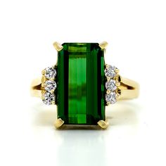 an emerald and diamond ring on a white background