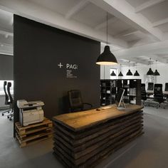 an office with black and white walls, wooden tables and chairs in front of the desks