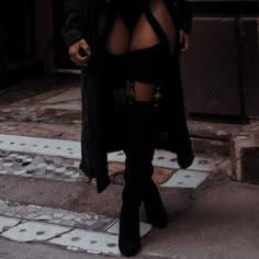 a woman wearing thigh high boots is walking down the street with her coat over her shoulders