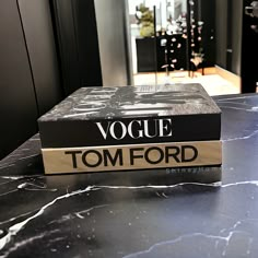 a book sitting on top of a table next to a black counter with a vase in the background