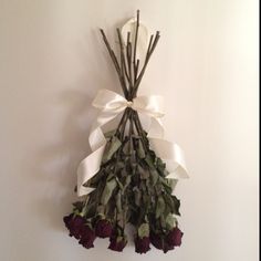 a bunch of dried flowers hanging on the wall with ribbon around it's ends