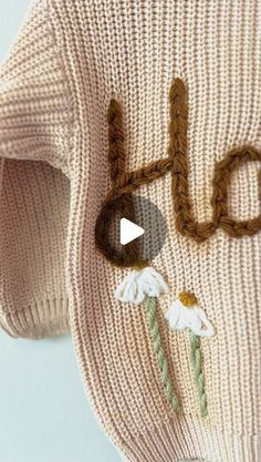 a close up of a knitted object with the word hello written on it and flowers