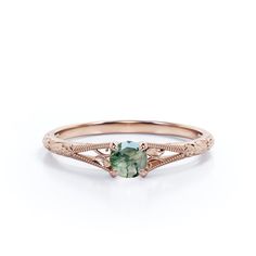 a rose gold ring with an oval green stone in the center and intricate filigrees