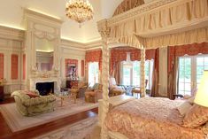 a large bedroom with four poster bed and chandelier